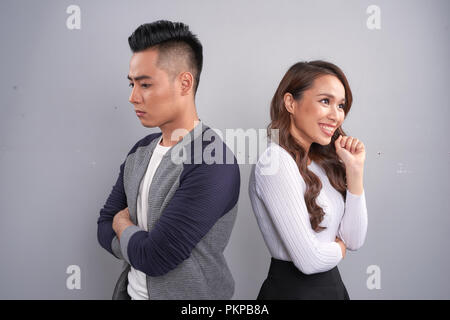 Portrait de malheureux frustrés couple standing back to back pas la parole aux autres après une dispute en étant debout sur fond gris. E négative Banque D'Images