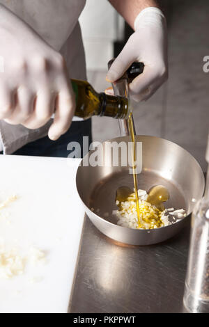 Le cuisinier verse de l'huile d'olive dans une poêle pour la cuisson Banque D'Images