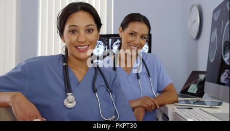 Smiling Hispanic and African American Nurses assis au poste informatique Banque D'Images