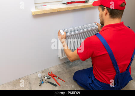 Plombier installation chauffage radiateur sur le mur à la maison Banque D'Images