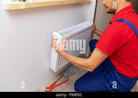 Services de plomberie - plombier installation chauffage radiateur sur le mur Banque D'Images
