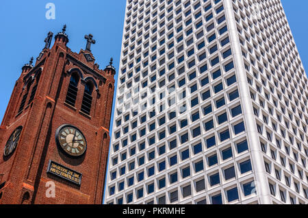 Ancienne église avec une horloge sur le côté d'un gratte-ciel moderne blanc Banque D'Images