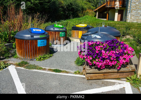 De grands bacs de recyclage plastique en couleur avec des fleurs violettes Chantemerle, Serre Chevalier ski resort, Briancon, France Banque D'Images