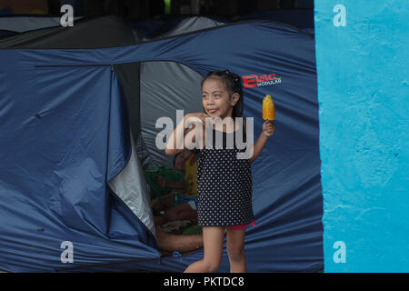 Manille, Philippines, de la RCN. 15 Sep, 2018. Un enfant, en dépit d'être dans les centres d'évacuation, de sourires après avoir obtenu leur secours.Le 14 septembre 2018, le super typhon Mangkhut a frappé les Philippines avec la vitesse du vent de 205 kilomètres par heure (km/h), et des rafales atteignant 255 km/h. Plus d'un millier de citoyens philippins dans tout le pays ont été touchés. Credit : ZUMA Press, Inc./Alamy Live News Banque D'Images