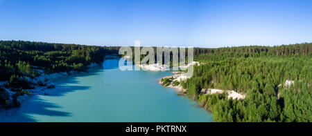 Drone aérien vue de la carrière de kaolin abandonnés avec le lac est apparu sur le fond, la surface de l'eau turquoise dans la soirée ensoleillée, envahi de Banque D'Images