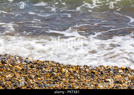 Sur la plage de Pagham harbour tide en venir. Surf de petites vagues cailloux et coquillages à la fin de l'été. Bord de l'eau apaisante simple droit UK côte sud. Banque D'Images