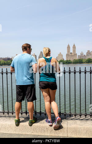 Central Park, New York, USA. Couple de prendre une pause de l'exécution de se pencher sur le lac. Banque D'Images