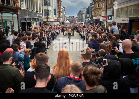 Leeds, Yorkshire / UK - 15 septembre 2018 : un artiste de rue à travers des cerceaux sauts incendie devant une grande foule sur la rue commerçante de Briggate Banque D'Images