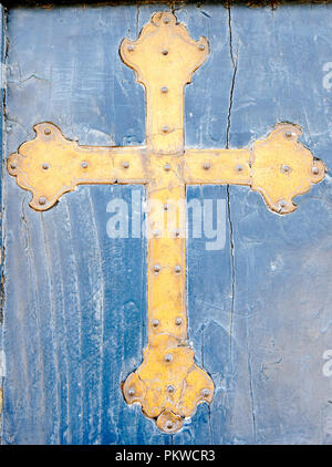 Crucifix en laiton sur bois bleu rétro arrière en Este, Padoue, Italie. Banque D'Images
