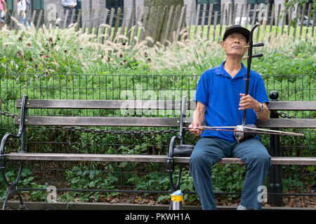 Un ancien de l'Amérique joue le ehru chinois sur un banc de parc de Washington Square à Manhattan, New York City. Banque D'Images