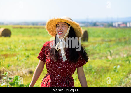 Asian girl détente en plein air dans un champ de blé en portant robe rouge Banque D'Images