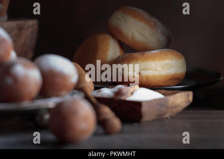 Des beignets sucrés avec des bâtons de cannelle avec du sucre en poudre sur une vieille table en bois. Focus sélectif. Banque D'Images