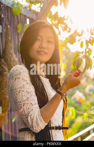 Jeune fille qui pose pour la caméra dans un jardin de fleurs. Banque D'Images