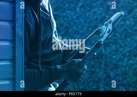 Un cambrioleur avec un coupe-boulon derrière un mur Banque D'Images