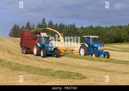 1986 Ford 7710 force 2 tracteur New Holland  + 525  + broyeur 1991 Ford 7810 Génération 3 avec remorque 8 tonnes ensilage collecte sur une ferme laitière en anglais Banque D'Images