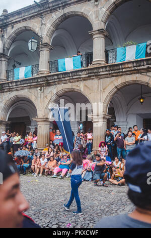 Antigua, Guatemala - 2018 : Jeune fille porte un drapeau bannière devant une foule comme elle marche dans une rue de parade de la Independencia" Dia Banque D'Images