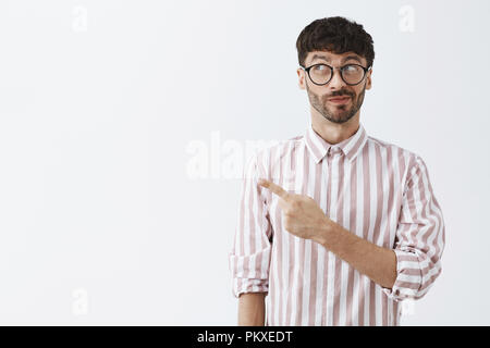 Jusqu'à la taille artistique et créatif de beau barbu souriant furtivement et avec un oeil et vers le coin en haut à gauche regardant avec intérêt et curiosité à intéressant et utile copy space Banque D'Images