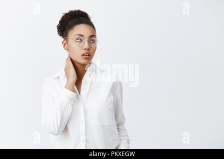 Être grand patron fatiguant. Offres et élégant africains-américains female office worker dans les verres et chemise blanche, en touchant le cou et le regard fatigué de rêve avec droit d'expression, une sensation de douleur dans le cou Banque D'Images
