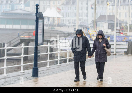 Aberystwyth, Pays de Galles, Royaume-Uni. 16 septembre 2018 UK Weather : personnes marchant le long de la promenade du front de mer à Aberystwyth , Pays de Galles sur un morne et humide dimanche après-midi de septembre. L'ouest de la France se prépare donc pour l'impact de la tempête Hélène, qui est prévu de faire la grève du jour au lendemain, le lundi, avec des vents soufflant jusqu'à 70 mi/h dans les zones exposées, , avec le risque de danger à la vie à partir de la projection de débris Photo © Keith Morris / Alamy Live News Banque D'Images