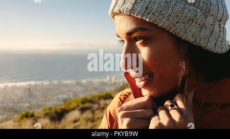 Close up of young female en appréciant les vêtements chauds seascape view from mountain top. Femme africaine en veste chaude et tricoté pac. Banque D'Images