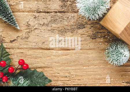 Vue de dessus de l'arbre de Noël et mini feuille rouge burry avec maison en bois jouet sur table en bois rustique avec des chutes de neige hiver.Maison de vacances partie.Cartes de vœux Banque D'Images