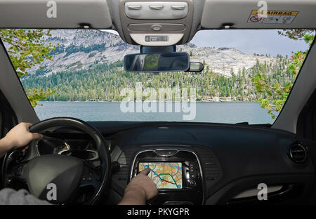 La conduite d'une voiture tout en utilisant l'écran tactile d'un système de navigation GPS vers une belle vallée verte et le lac dans le Parc National de Yosemite (Californie), Banque D'Images