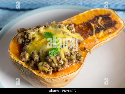 Butternut au four farcies aux lentilles, hacher la viande et les légumes avec fromage fondu sur le dessus Banque D'Images