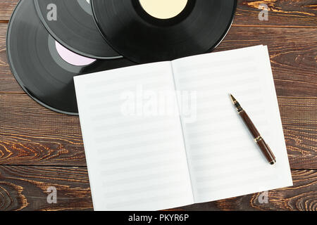 Les disques vinyles et d'ordinateurs portables pour les notes de musique. Note de musique vierge papier, stylo et vinyles. Matériel de musique sur fond de bois. 24 de musicien. Banque D'Images