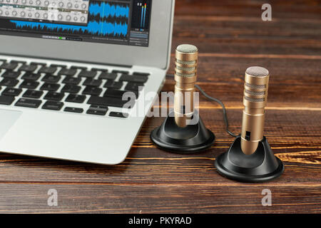 Ordinateur portable et l'enregistrement stéréo micro. Les microphones à condensateur stéréo mini ordinateur portable et sur fond de bois brun. Concept de technologies modernes. Banque D'Images