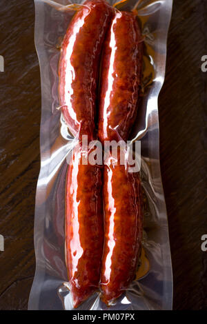 Épicé rouge saucisses chorizo méditerranéennes espagnoles en vinyl emballées sous vide avec l'arrière-plan de table en bois Banque D'Images