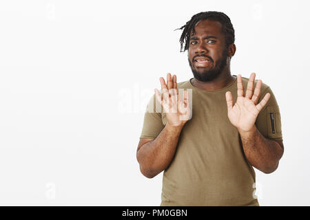 Mécontent intense guy dodus attrayant avec une peau sombre, de palmiers dans l'abandon, montrant la réticence à participer à l'événement, de rejet ou d'être dégoûté de l'offre quelque chose de plus de mur gris Banque D'Images