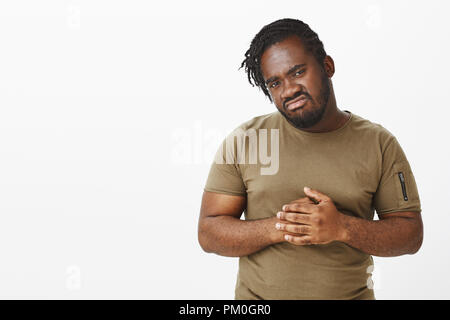 Taille plan sur déplut sombre africains-américains dans l'homme t-shirt militaire, se frottant les doigts et déçu de l'appareil photo, les sourcils et l'expression de dégoût, quelque chose de troublant Banque D'Images