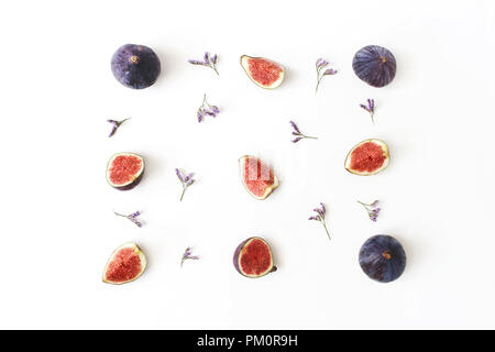 Figues violettes frais mûrs. Photo de l'alimentation. La composition créative de l'ensemble et les tranches de fruits exotiques et de fleurs violet limonium sur fond blanc tableau arrière-plan. Motif floral. Mise à plat, vue de dessus. Banque D'Images