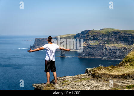 Homme profitant de la vue sur l'océan depuis les falaises de Moher, falaises de mer situées à la limite sud-ouest de la région de Burren dans le comté de Clare, Irlande Banque D'Images