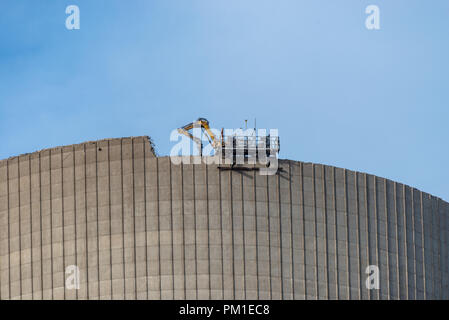 Démolition de la cheminée atomique. Pelle hydraulique avec commande à distance fonctionne à partir de la cisaille ci-dessus. Banque D'Images