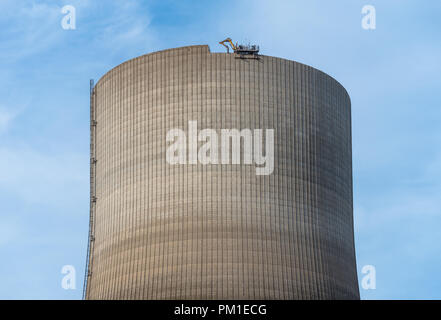 Démolition de la cheminée atomique. Pelle hydraulique avec commande à distance fonctionne à partir de la cisaille ci-dessus. Banque D'Images