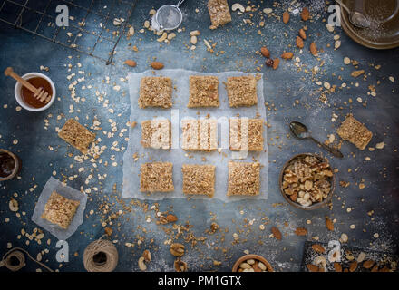 Des tranches au caramel du papier sulfurisé, avec un fond bleu texturé y compris les noix, graines et céréales une flatlay frais généraux de droit, partie d'une série Banque D'Images