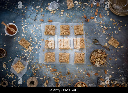 Des tranches au caramel du papier sulfurisé, avec un fond bleu texturé y compris les noix, graines et céréales une flatlay frais généraux de droit, partie d'une série Banque D'Images