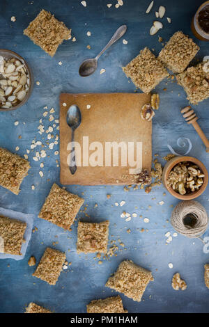 Des tranches au caramel papier cuisson sur un fond bleu texturé avec des noix, graines et céréales une flatlay frais généraux de droit Banque D'Images