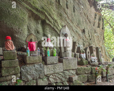 Statues sacrées, avec des bonnets rouges, des bouteilles de thé offerts, Iyadaniji 71 temple, temple 88 Shikoku pèlerinage, Kagawa, Japon Printemps 2018 Banque D'Images