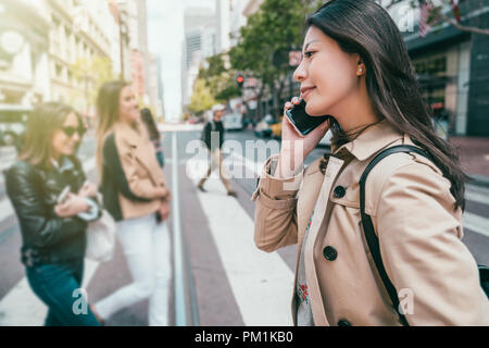 Beautiful business woman smiling joyeusement et effectuer un appel téléphonique tout en traversant la rue au centre-ville. Banque D'Images