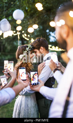 Les clients avec les smartphones de prendre photo de mariés à réception de mariage à l'extérieur. Banque D'Images