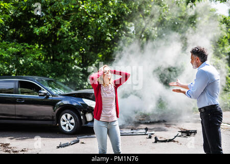 La colère d'un homme mûr et jeune femme soutenant après un accident de voiture. Banque D'Images