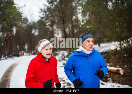 Une vue de face du couple jogging en hiver neige la nature. Banque D'Images