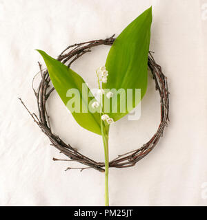 Composition florale. Couronne faite d'roools, feuilles, et de fleurs de muguet tissu sur fond blanc. Style rustique du décor à la maison, télévision, de laïcs Banque D'Images