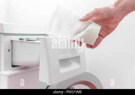 Libre d'un homme part remplir détergent dans le tiroir d'un lave-linge. Banque D'Images
