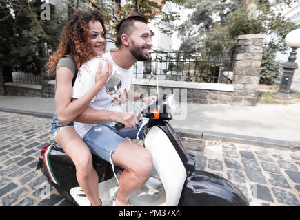 Jeune couple élégant se trouve un scooter dans la rue. Banque D'Images