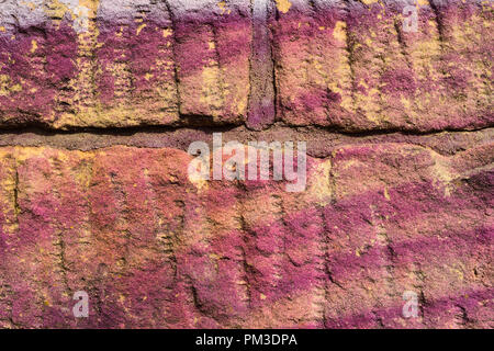 Un vieux mur avec graffiti violet Banque D'Images