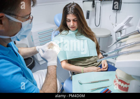 Processus de démonstration de médecin professionnel le brossage des dents saines pour jeune femme assise au fauteuil. Banque D'Images