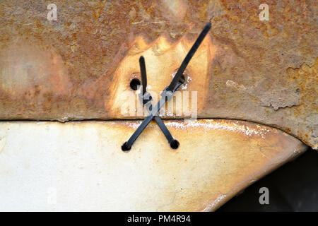 Photo détaillée de deux attaches de câble tenant un bouclier arrière de très vieille voiture rouillée. Banque D'Images